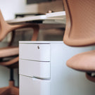Light gray filing cabinet with brown chairs in a room setting