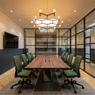 Modern conference room with wooden table and green chairs.