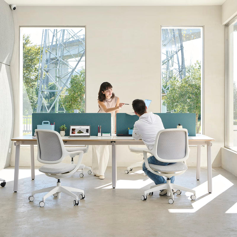 Load image into Gallery viewer, Two people sitting at a desk in a modern office with large windows.

