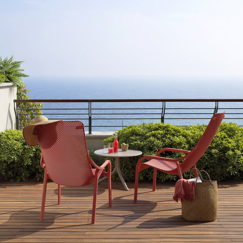 Load image into Gallery viewer, Two red chairs on a wooden deck with a scenic ocean view.
