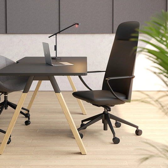 Modern office setup with a black desk, chair, and laptop in a minimalistic room.
