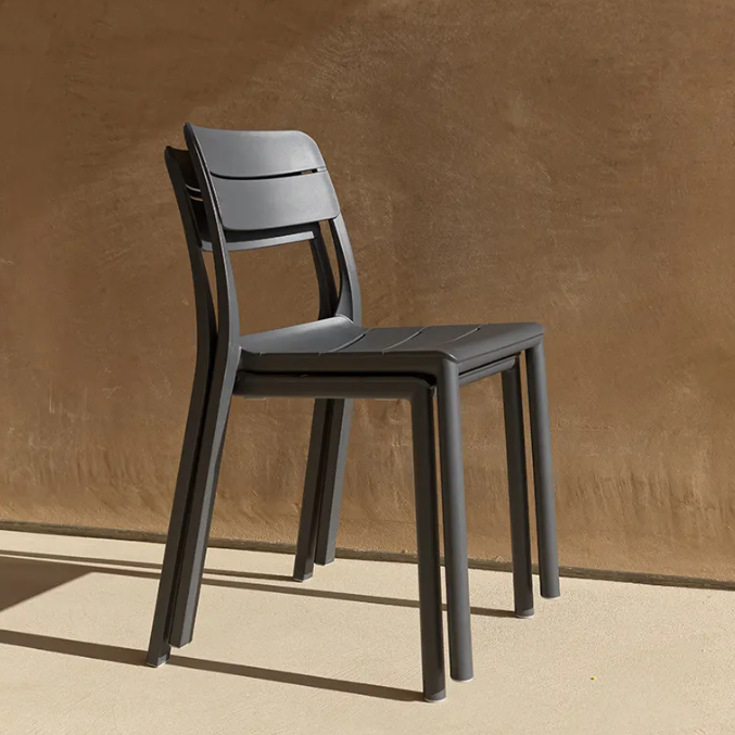 Load image into Gallery viewer, Two dark gray chairs stacked against a brown wall.
