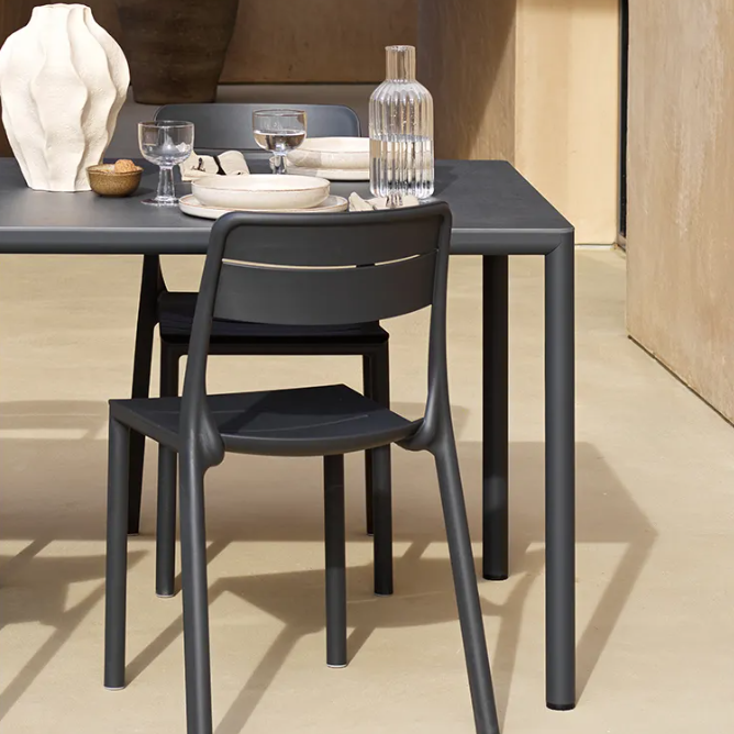 Load image into Gallery viewer, Modern black dining table with chairs in a minimalistic setting
