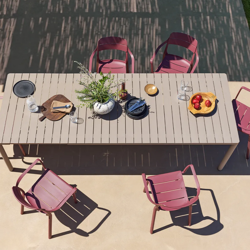 Load image into Gallery viewer, Outdoor dining setup with a wooden table and pink chairs on a patio.
