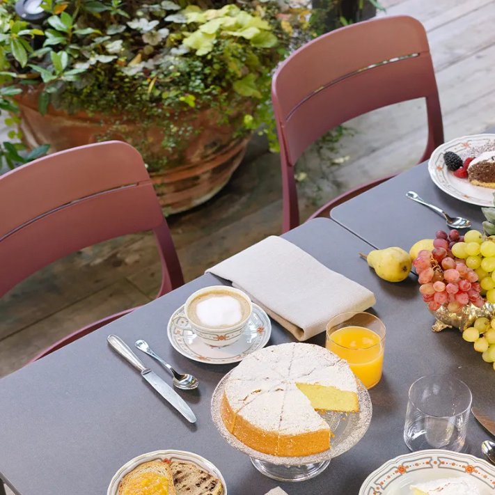 Load image into Gallery viewer, Outdoor dining table with food, drinks, and chairs on a patio.
