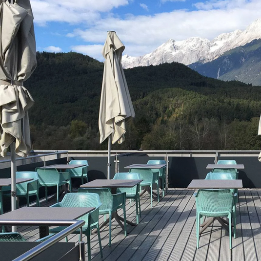 mint outdoor chairs and taupe tables with mountains and umbrellas