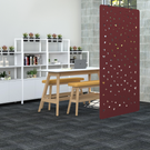 Modern office space with a red perforated screen, white bookshelf, and wooden desk.